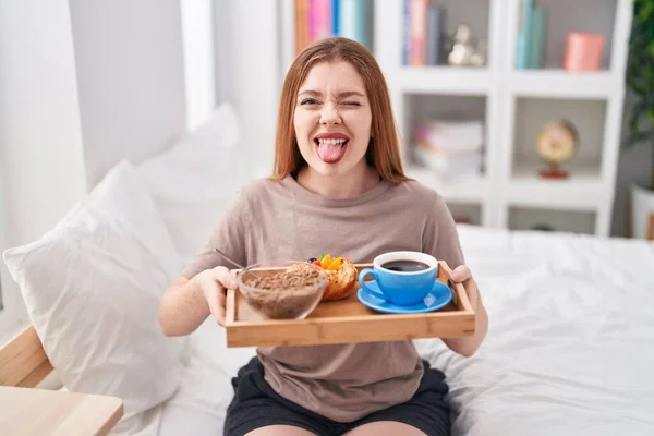 Redhead Woman Wearing Pajama Holding Breakfast Tray Sticking Tongue Out — Fotografia de Stock