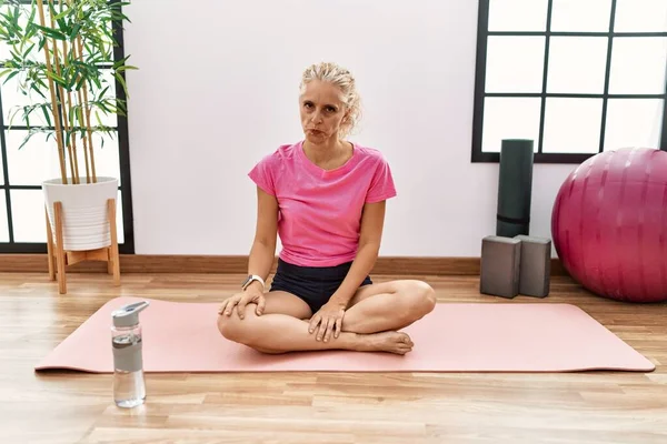 Middle Age Blonde Woman Sitting Yoga Mat Skeptic Nervous Frowning — Stock Photo, Image