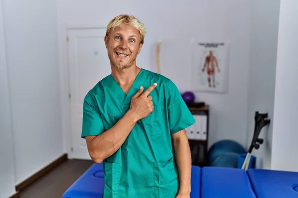 Young Blond Man Wearing Physiotherapist Uniform Standing Clinic Cheerful Smile — Stockfoto