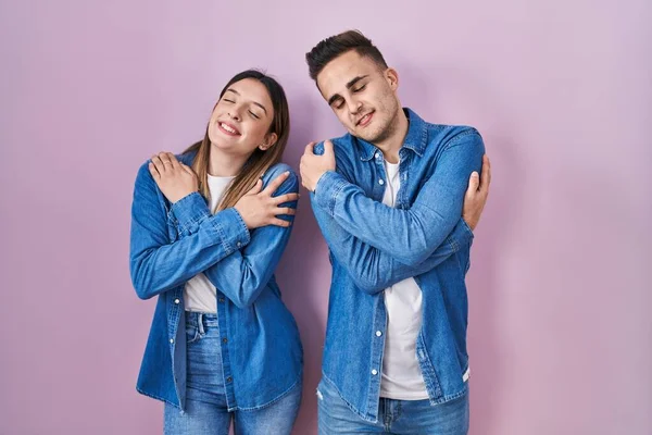 Young Hispanic Couple Standing Pink Background Hugging Oneself Happy Positive — Stock Photo, Image