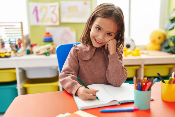 Adorable Hispanic Girl Preschool Student Sitting Table Writing Notebook Kindergarten — Fotografia de Stock