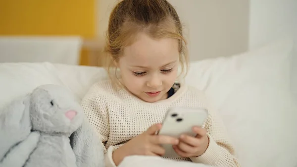 Adorable Blonde Girl Using Smartphone Sitting Bed Bedroom — Stock Photo, Image