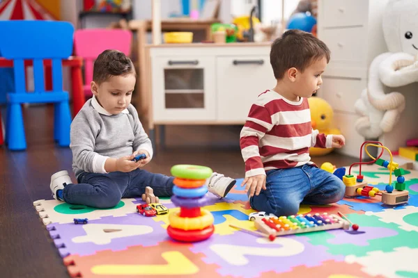幼稚園の床に座って車のおもちゃを保持木琴を演奏する2人の子供 — ストック写真