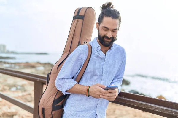 Young Hispanic Man Musician Using Smartphone Holding Guitar Case Seaside — Stock Photo, Image