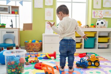 Adorable hispanic boy standing at kindergarten