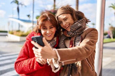 Two women mother and daughter make selfie by smartphone at street