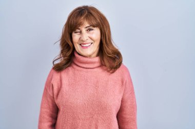 Orta yaşlı İspanyol bir kadın izole edilmiş arka planda durmuş kameraya seksi bir ifadeyle bakıyor, neşeli ve mutlu bir yüzle.. 