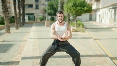 Genç İspanyol adam parkta karate dövüşçüsü eğitimi alıyor.