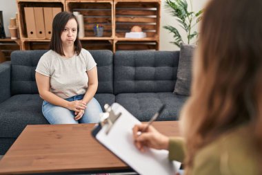 Hispanic girl with down syndrome doing therapy relaxed with serious expression on face. simple and natural looking at the camera. 