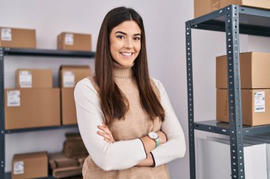 Genç, güzel, İspanyol bir kadın. İş adamı. Ofiste kollarını kavuşturup el kol hareketi yapıyor.