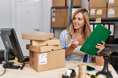 Genç sarışın kadın ecommerce iş işçisi ofisteki panoya yazıyor.