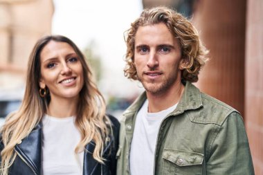 Erkek ve kadın bir arada durarak gülümsüyor.