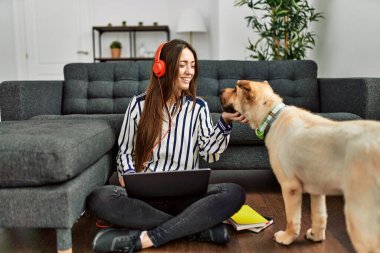 Genç İspanyol kadın dizüstü bilgisayar kullanıyor evde köpekle oturuyor.