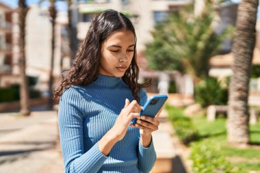 Genç Afro-Amerikan kadın parkta akıllı telefon kullanıyor.