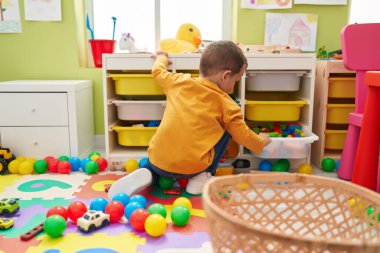 Adorable caucasian boy holing cube with construction blocks at kindergarten
