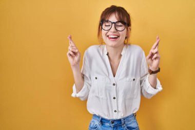 Sarı arka plan üzerine gündelik tişört giyen genç ve güzel bir kadın umut ve gözler kapalı bir şekilde gülümseyerek işaret ediyor. Şans ve batıl inançlar. 