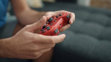 Evdeki kanepede oturan İspanyol asıllı genç oyun oynuyor.