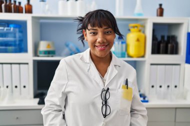 Young beautiful latin woman scientist smiling confident standing at laboratory