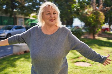 Orta yaşlı, sarışın, gülümseyen, kendine güvenen bir kadın.