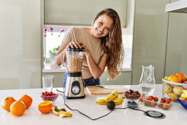 Genç, güzel İspanyol kadın mutfakta sebze suyu ve blender hazırlıyor.