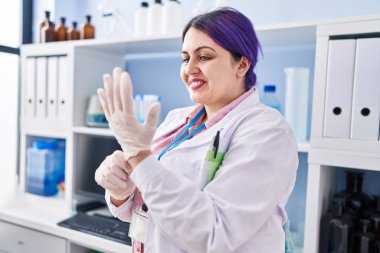 Young beautiful plus size woman scientist smiling confident wearing gloves at laboratory