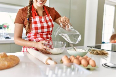 Genç, güzel, İspanyol bir kadın. Mutfakta un dökerek kendinden emin bir şekilde gülümsüyor.