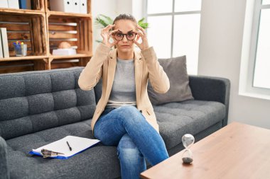 Young woman working at consultation office trying to open eyes with fingers, sleepy and tired for morning fatigue 