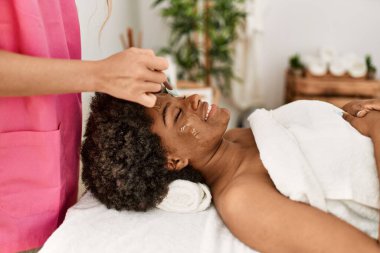 Genç Afrikalı Amerikalı kadın, güzellik merkezinde kendine güvenen bir şekilde gülümsüyor.