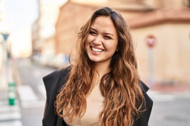 Young beautiful hispanic woman smiling confident looking to the side at street