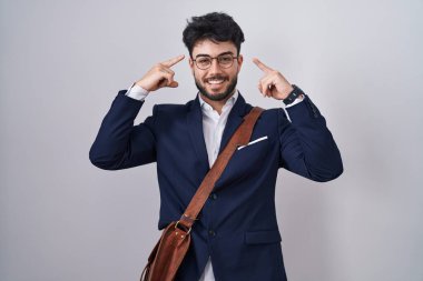 Hispanic man with beard wearing business clothes smiling pointing to head with both hands finger, great idea or thought, good memory 