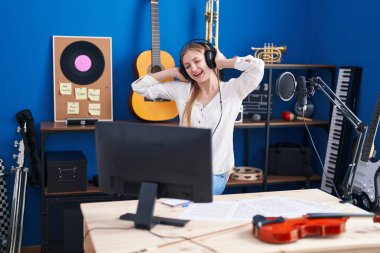 Young caucasian woman artist listening to music and dancing at music studio