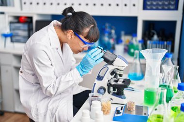 Laboratuvarda mikroskop kullanan genç ve güzel İspanyol bilim kadını.