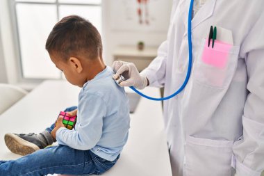 Mother and son pediatrician and patient auscultating respiratory system at clinic