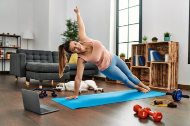 Evde yoga dersi aldığı için kendinden emin gülümseyen genç bir kadın.