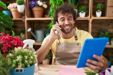 Çiçekçide dokunmatik ped kullanarak konuşan genç İspanyol çiçekçi.
