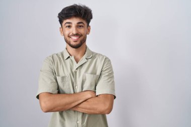 Arab man with beard standing over white background happy face smiling with crossed arms looking at the camera. positive person. 