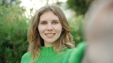 Young blonde woman smiling confident making selfie by camera at park
