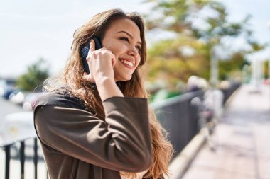 Genç, güzel İspanyol kadın gülümsüyor. Parktaki akıllı telefondan konuşuyor.