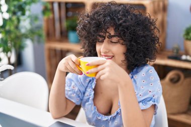 Young middle east woman using laptop and drinking coffee at home
