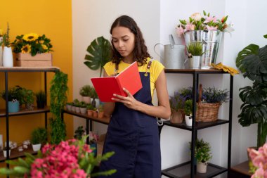 Young african american woman florist writing on notebook standing at flower shop