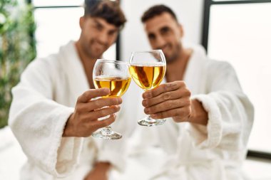 Şampanyayla kadeh kaldıran iki İspanyol erkek güzellik merkezinde masaj masasında oturuyor.