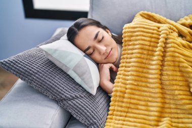 Genç İspanyol kadın kanepede yatıp evde uyuyor.