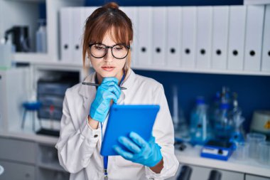 Young woman scientist using touchpad at laboratory