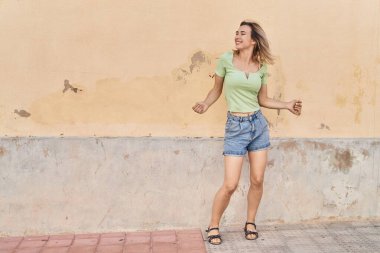 Young woman smiling confident dancing at street