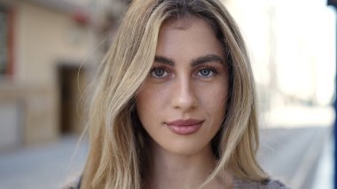 Sokakta ciddi bir ifadeyle duran genç sarışın kadın.