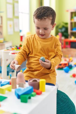Adorable caucasian boy playing with toys sitting on floor at kindergarten