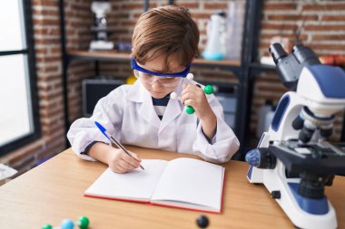 Not defterine yazıp laboratuvar sınıfında molekülleri tutan sevimli İspanyol çocuk.