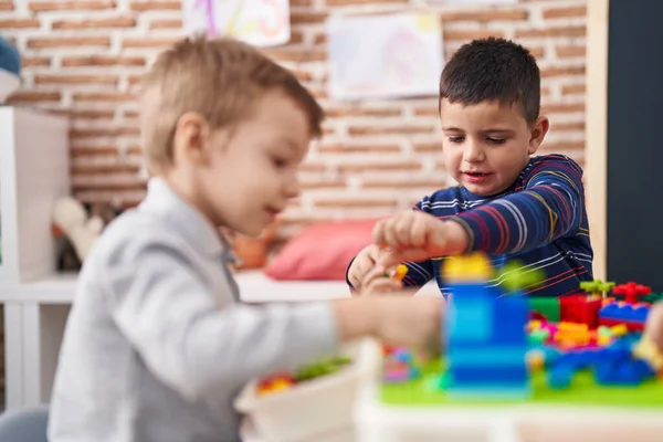 2人の子供が幼稚園のテーブルの上に座って建設ブロックで遊んでいます — ストック写真
