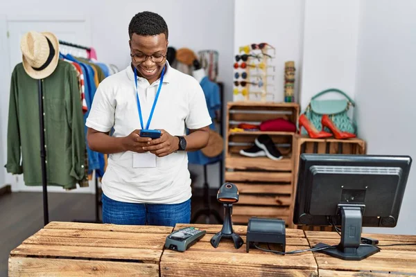 Young african man working as shop assistance using smartphone at retail shop