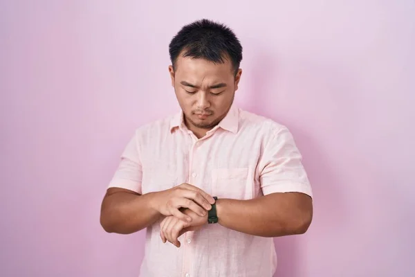 Китайский Молодой Человек Стоит Розовом Фоне Проверяя Время Наручных Часах — стоковое фото